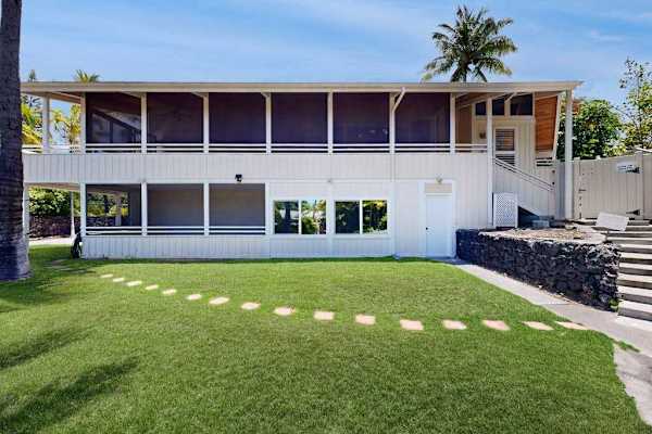 Landscaped lawn frames the home with palms and stepping stones
