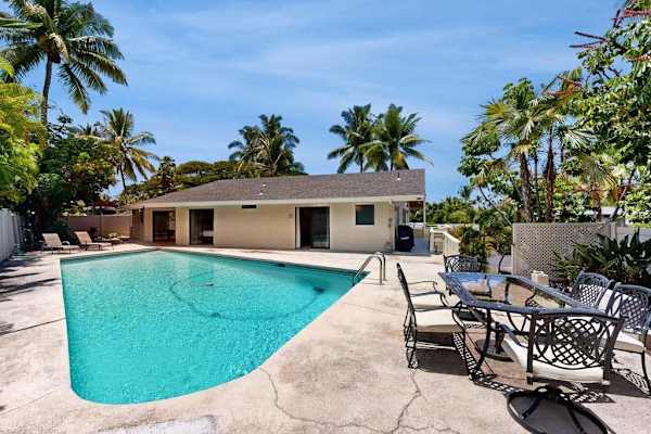 Poolside patio offers shaded seating beside a sparkling island home
