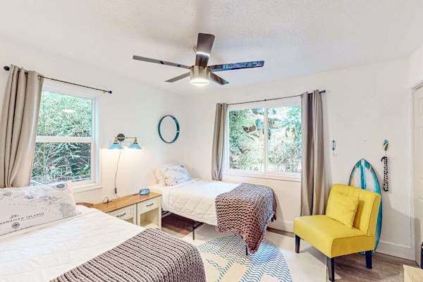 Guest room with two twin beds, ceiling fan and plenty of natural light.
