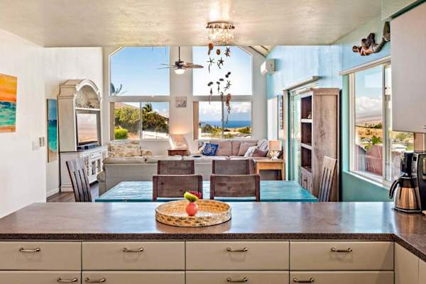 Large open update kitchen with stainless steel appliances with a view to the living room and light from the floor to ceiling windows.