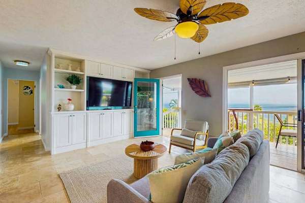 Living room seating faces windows with tropical scenery and breezes