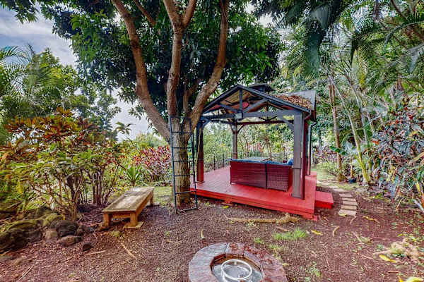 Garden bench offers shaded seating beneath tropical trees and foliage
