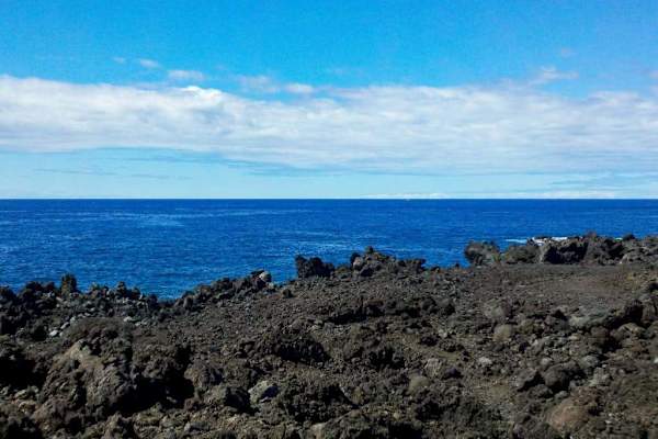 Rugged lava shoreline frames sweeping Pacific views beneath island skies
