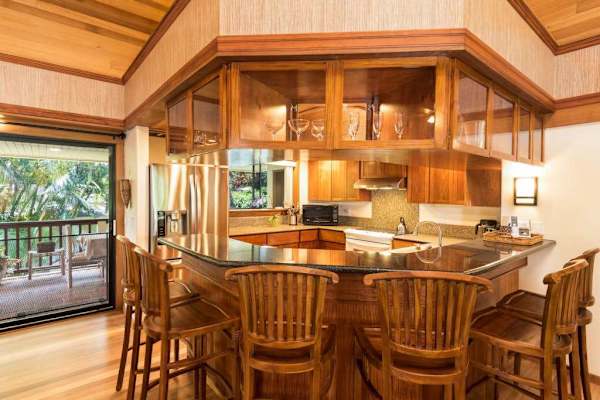 Wooden kitchen presents island seating, cabinetry, and practical appliances throughout