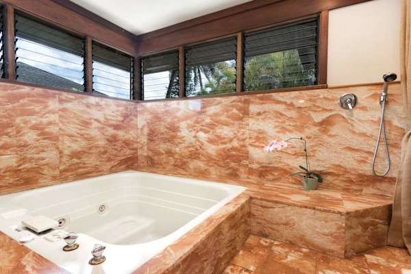 Marble bathroom features a deep bathtub, tiled walls, and windows