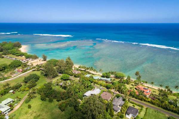 Aerial coastline view showcases turquoise water, green hills, and sandy beaches