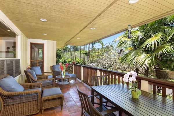 Covered patio offers comfortable furnishings, garden views, and breezy relaxation