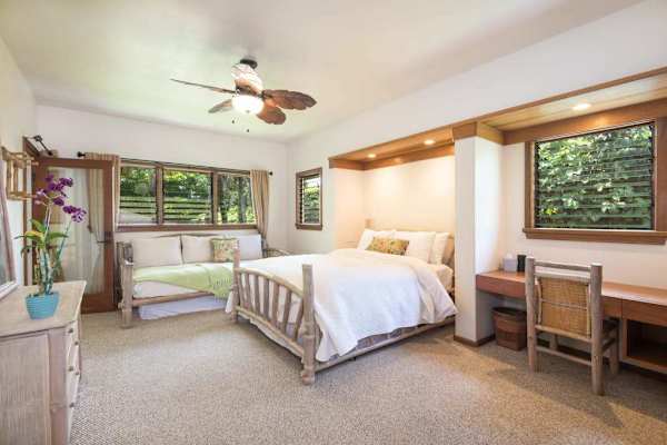 Bright bedroom offers comfortable bedding, practical furnishings, and garden views