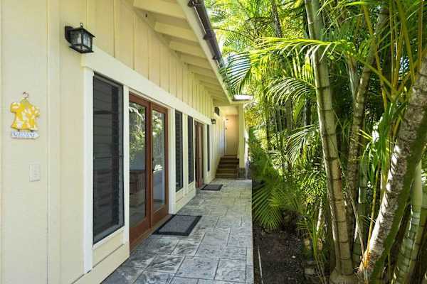 Side exterior walkway passes beneath lush foliage beside the residence