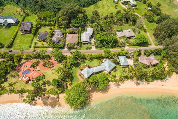 Bird’s-eye property view reveals tropical grounds, pathways, and coastal shoreline