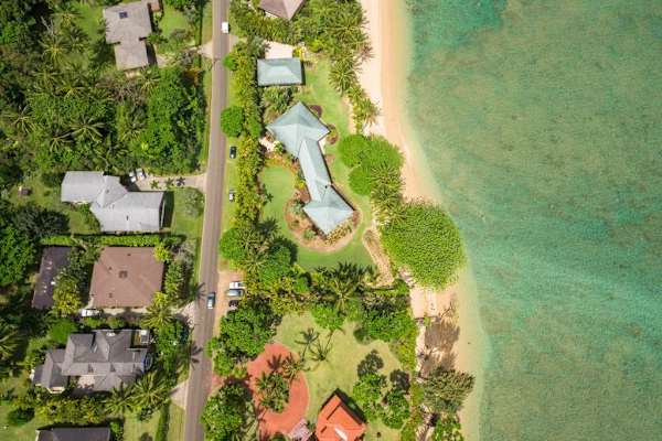 Aerial property view showcases buildings, greenery, lawn, and coastal surroundings