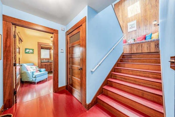 Wooden staircase leads upstairs beside walls and a bedroom entrance
