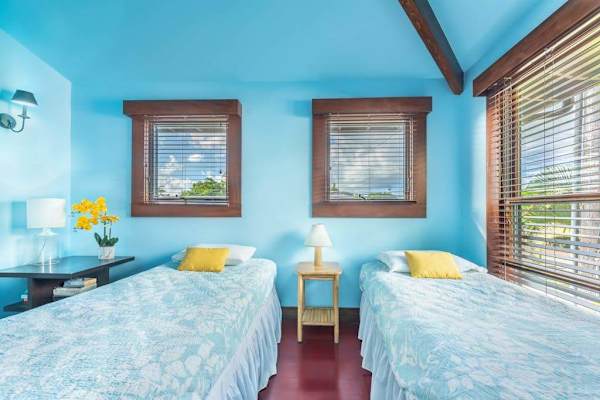Modern bedroom features twin beds, fresh linens, and garden views