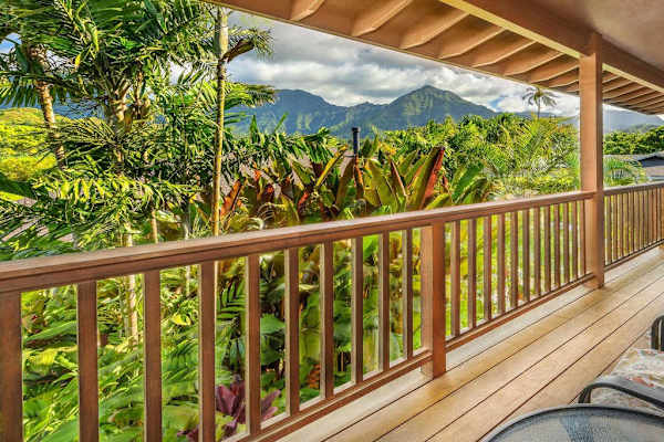 Covered balcony overlooks lush tropical foliage and dramatic mountain scenery