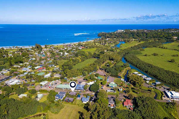 Aerial neighborhood view reveals coastal homes, fields, and distant ocean