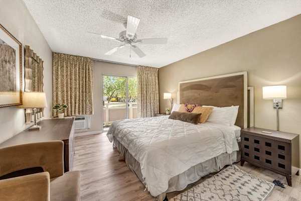 Primary Bedroom Featuring King Bed, Dresser, Ceiling Fan, and Sliding Patio Access