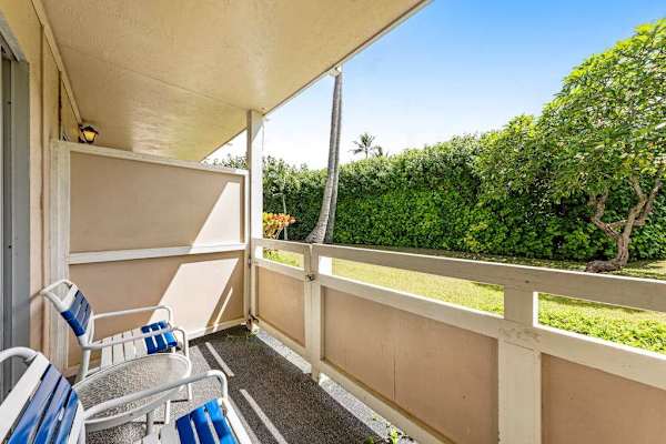 Private Covered Balcony Patio with Seating and View of Lush Tropical Lawn.