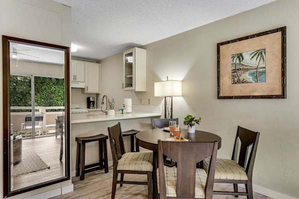 Dining Area with Wooden Table and Chairs Adjacent to Kitchen Breakfast Bar