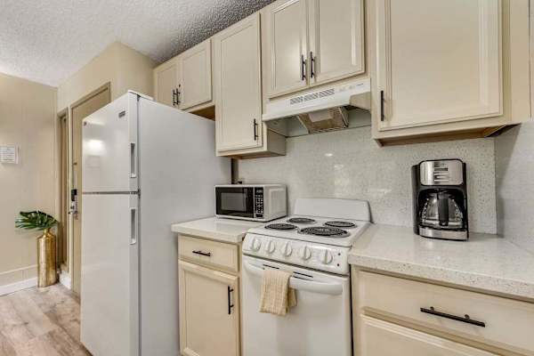 Fully Equipped Kitchen View Showing Refrigerator, Stove, and Upper Cabinets
