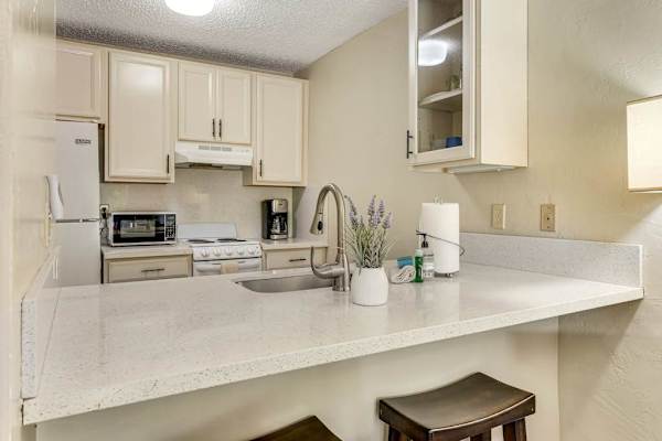 Fully Equipped Kitchen with Modern Appliances, White Cabinets, and Breakfast Bar