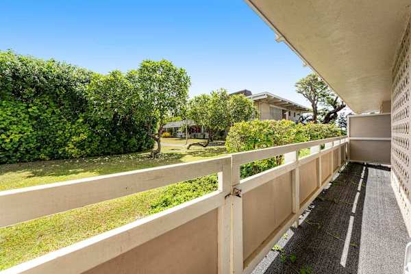 Long Covered Private Balcony Overlooking Green Lawn and Tropical Foliage