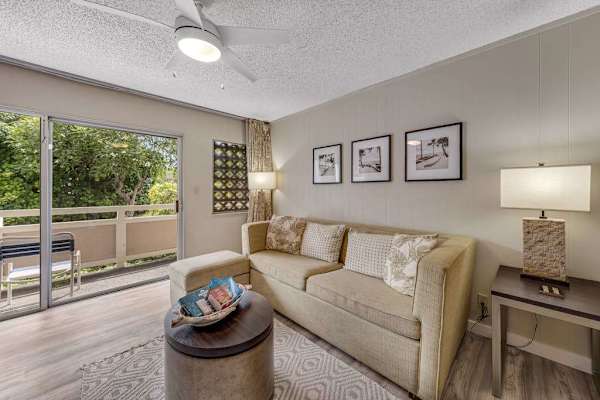 Bright Living Room with Neutral Sofa, Ceiling Fan, and Direct Access to Private Balcony