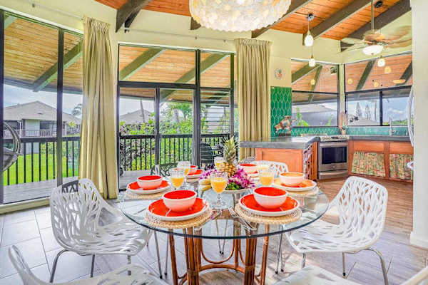 Elegant dining area with vaulted wood ceilings and tropical touches, opening to a screened lanai