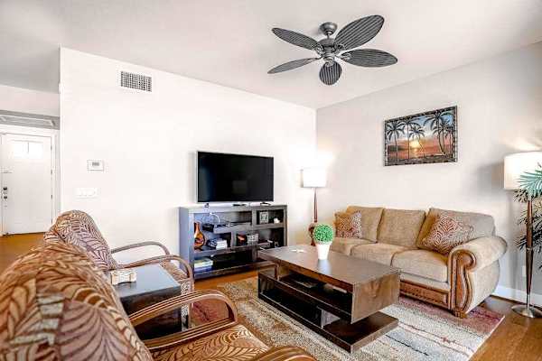 Spacious living room with comfortable seating, flat screen tv and natural light streaming in from the private lanai.