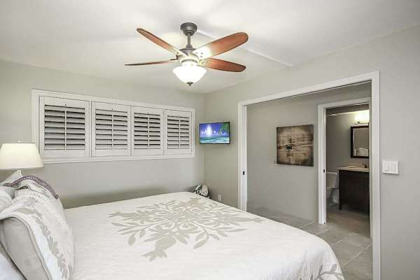 Master bathroom with king bed, flat screen tv and a ceiling fan.