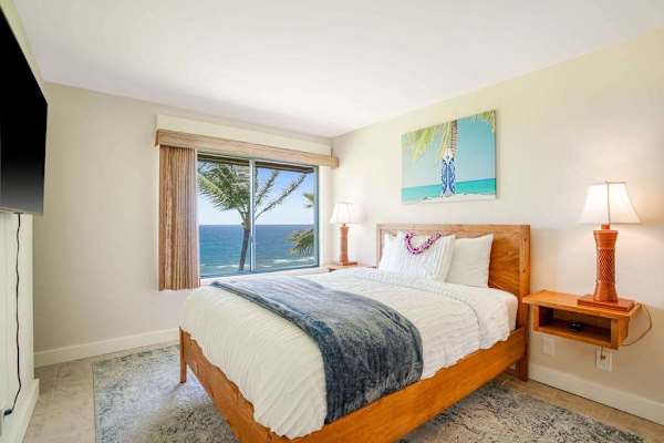 Cozy bedroom featuring a queen bed, warm lighting, and tropical ocean views