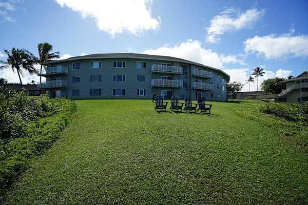 Building exterior with lush grounds and ocean backdrop