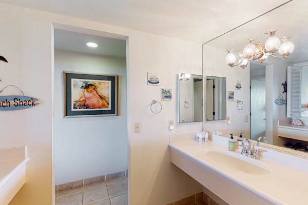 Bathroom vanity features mirror lighting polished fixtures and spacious counters