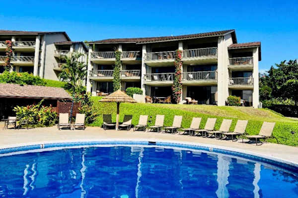 Resort swimming pool reflects balconies beneath clear tropical sunshine outside