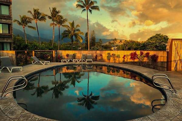 Sunset pool mirrors swaying palms beside inviting island lounge chairs