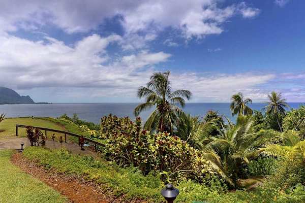 Sunset aerial view illuminates the residence, coastline, and surrounding greenery