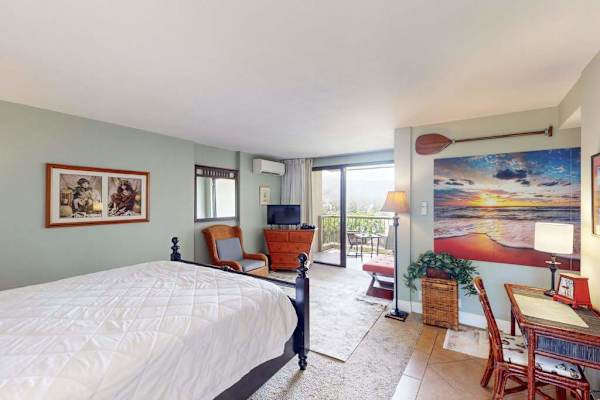 Bright studio includes comfortable bedding, dresser, artwork, and peaceful decor