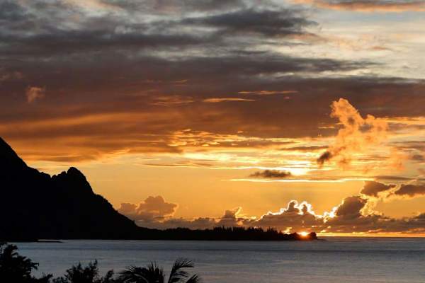 Golden sunset paints ocean clouds, distant mountains, and evening skies