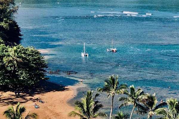 Coastal waters sparkle beneath blue skies, boats, and island scenery