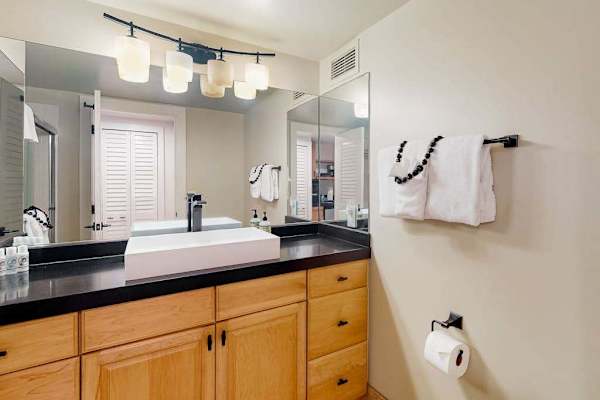 Bathroom vanity features a spotless sink, mirrors, ample lighting, and storage