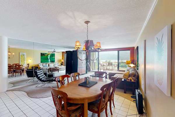 Open dining area connects with kitchen, seating, and tropical views