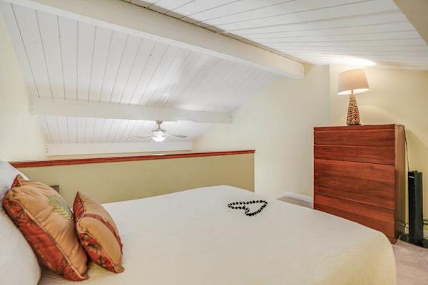 Inviting bedroom includes comfortable bed, dresser, ceiling fan, and carpeting