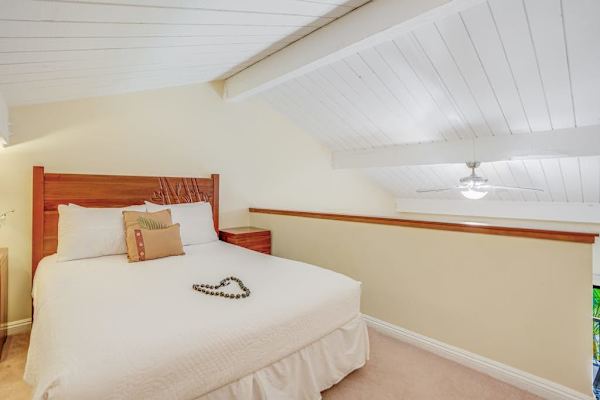 Bedroom offers comfortable bedding, ceiling fan, and warm wooden accents