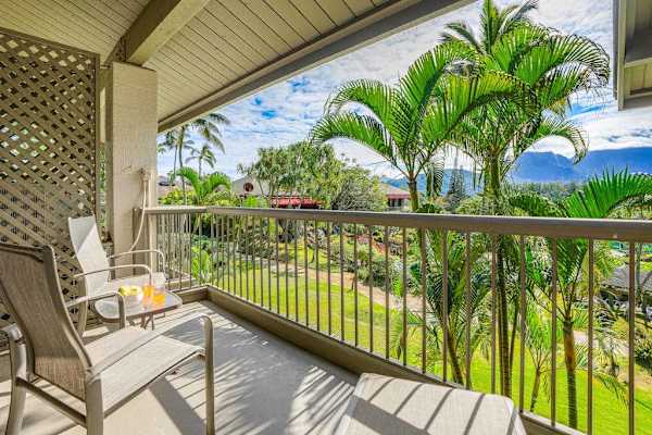 Covered balcony offers outdoor seating, tropical greenery, and mountain views