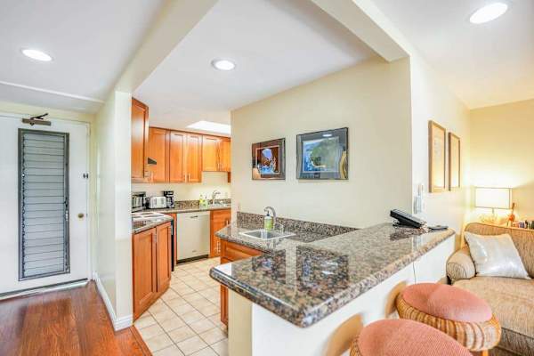 Modern kitchen features granite countertops, bar seating, and ample cabinetry
