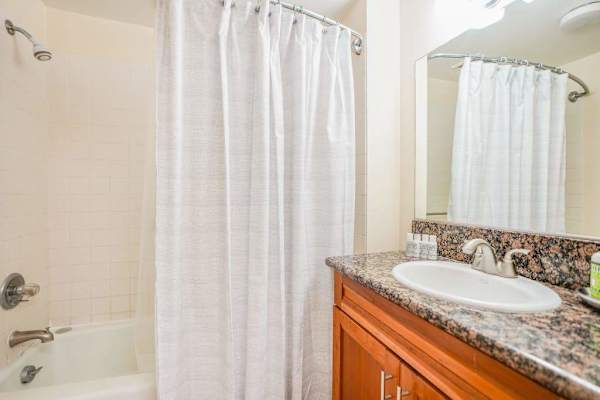 Bathroom includes glass shower, granite vanity, and bright overhead lighting