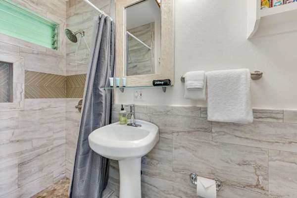 Bright full bathroom with a walk-in shower and fresh towels.