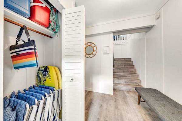 Storage keeps beach gear organized beside stairs and hallway