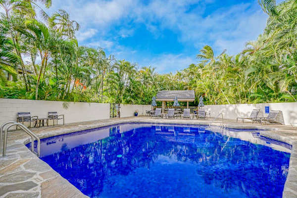 Sparkling Resort Swimming Pool Surrounded by Tropical Palms & Sun Loungers