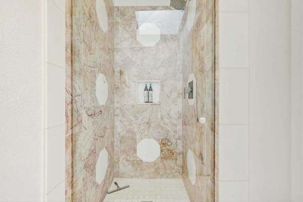  walk-in shower features large-format beige veined porcelain tiles