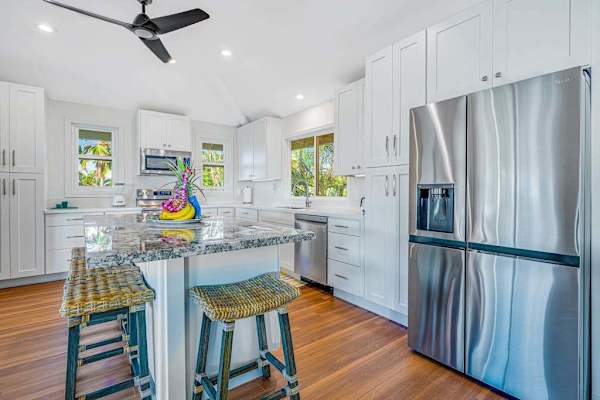 Modern kitchen with stainless steel refrigerator, island barstools, and hardwood flooring